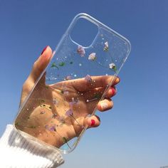 a woman holding up her phone case with flowers on it and blue sky in the background