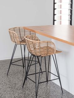 two wicker bar stools sitting on top of a counter