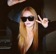 a woman wearing sunglasses making the peace sign