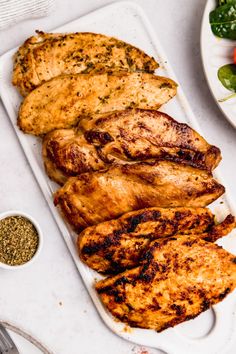 grilled chicken and vegetables on a platter next to a bowl of seasoning