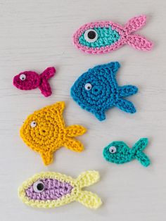 four crocheted fish sitting on top of a white table next to each other