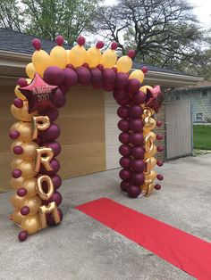 an arch made out of balloons with the word love spelled in gold and purple letters