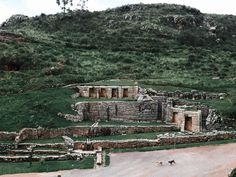 an ancient structure in the middle of a grassy hill