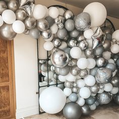 a room filled with lots of silver and white balloons