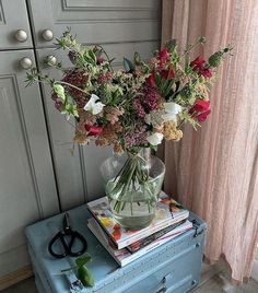 a vase filled with flowers sitting on top of a blue suitcase