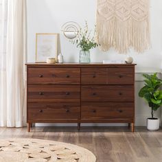 a wooden dresser sitting on top of a hard wood floor next to a potted plant