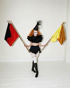 a woman dressed as a witch holding two flags