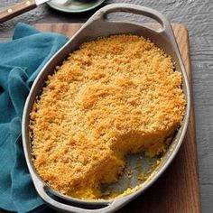 a cake in a pan on top of a wooden cutting board with a blue cloth