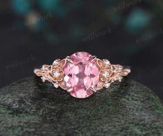 an oval pink sapphire and diamond ring on top of a rock