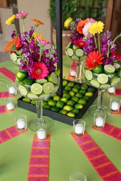 the table is decorated with limes, flowers, and candles for guests to sit at