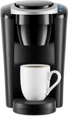 a black coffee maker with a white cup