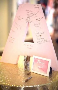 a pink letter with writing on it sitting next to a small glass jar filled with pencils