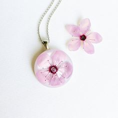 This cherry flower necklace is made from a real cherry flower picked up from the place where I live. A unique sakura necklace as the most unique birthday gift idea for women. In general, a cherry flower necklace (japanese flower necklace) is an outstanding full of significance complement for you. This sakura blossom necklace is part of my pale pink jewelry. The hypoallergenic stainless steel and the high-gloss crystalline resin gives this cherry flower necklace a precious and enamelled look. Use Elegant Blossom Color Necklace For Gift, Elegant Pink Necklace For Gift, Delicate Blossom Flower Pendant Necklace, Delicate Blossom Color Flower Pendant Necklace, Delicate Blossom-colored Jewelry For Gifts, Delicate Blossom Colored Jewelry As Gift, Delicate Blossom Jewelry Gift, Blossom Color Flower Shape Jewelry With Flower Charm, Blossom Color Jewelry With Flower Charm