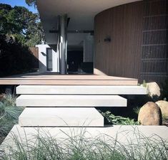 a modern house with grass and rocks in the front yard, as well as steps leading up to it