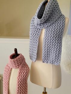 two knitted scarves sitting on top of a white mannequin head stand