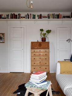 a bedroom with a bed, dresser and bookshelf full of books on top of it