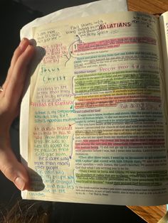 a person holding an open bible with words written on it and writing down the pages