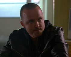 a man in a leather jacket looking at the camera