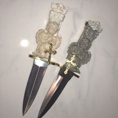 two knives with skulls on them are next to each other and one is holding a cross