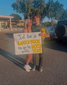 a man and woman holding a sign that says i'd be a lucky duck to go to moo with you