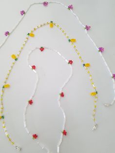 three necklaces made out of plastic beads and flowers on a white surface with one bead in the shape of a dog