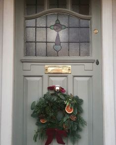 a wreath on the front door of a house with a stained glass window above it