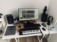 there is a computer on the desk with headphones and music equipment next to it