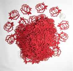 a pile of red paper cut outs sitting on top of a white table next to a coin