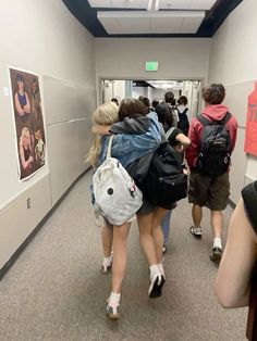 several people walking down a hallway with backpacks on their back and one person holding onto another