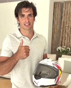 a man giving the thumbs up while holding a motorcycle helmet