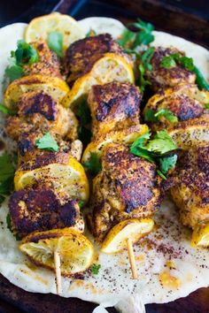 chicken skewers with lemons and parsley on a tortilla shell