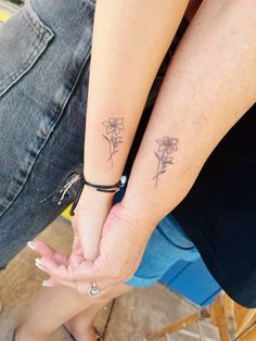 two people holding hands with small tattoos on their arm and wrist, one is holding the other