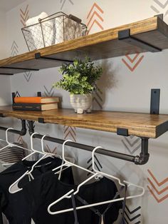 two shelves with clothes hanging on them and a potted plant in the corner next to it