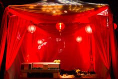 a red canopy with lanterns hanging from it's sides and lights on the ceiling