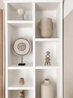 white shelves with vases, plates and other items on them in a living room