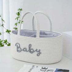 a white basket sitting on top of a table next to a book and some plants