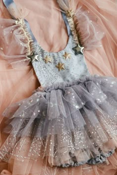 a dress made out of tulle with stars on the top and bottom, sitting on a pink blanket