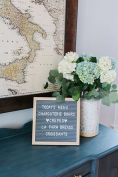 there is a vase with flowers on top of the table next to a sign that says today's menu