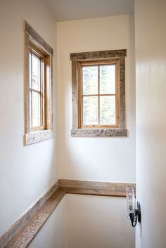 the corner of a room with a window and wooden trim on the wall next to a door