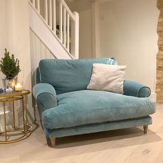 a blue couch sitting in front of a stair case next to a table with candles on it