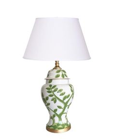 a green and white vase lamp with a white shade on it's side, against a white background