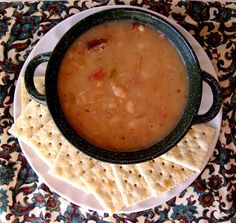 a bowl of soup on a plate with crackers