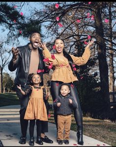 a family poses for a photo on the sidewalk with hearts flying in the air above them