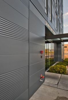 A close-up profile of a commercial building that's clad in grey Nichiha panels. Several of the panels across the facade are ribbed panels, giving the building a bold visual texture effect. Architectural Wall Panel, Architectural Wall, Case Study Design, Commercial Construction, Fiber Cement, Commercial Architecture, Don't Settle, Residential Design, Commercial Property