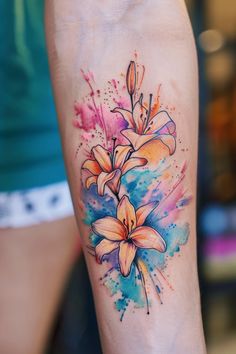 a watercolor tattoo with lilies on the arm