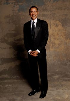 a man in a black suit and tie posing for a photo with his hands on his hips