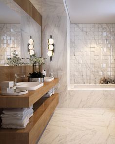 a bathroom with two sinks and a bathtub next to each other in front of a marble tiled wall