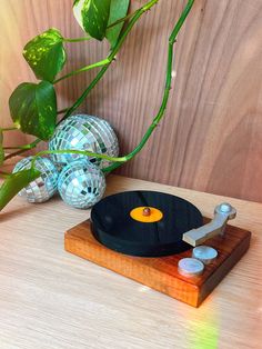 a record player sitting on top of a wooden table next to a potted plant