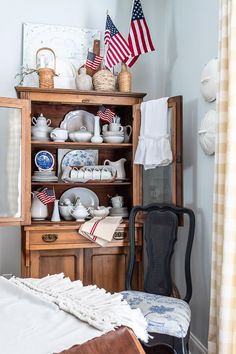 an old china cabinet with american flags and other patriotic items on it's shelves