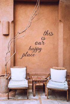 two chairs sitting next to each other in front of a wall with writing on it